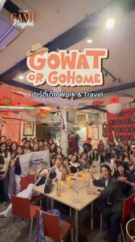 ภาพหมู่คนจำนวนมากถือธง GoWAT ในร้านที่แต่งด้วยของตกแต่งหลากสี ในงาน Social Game Night